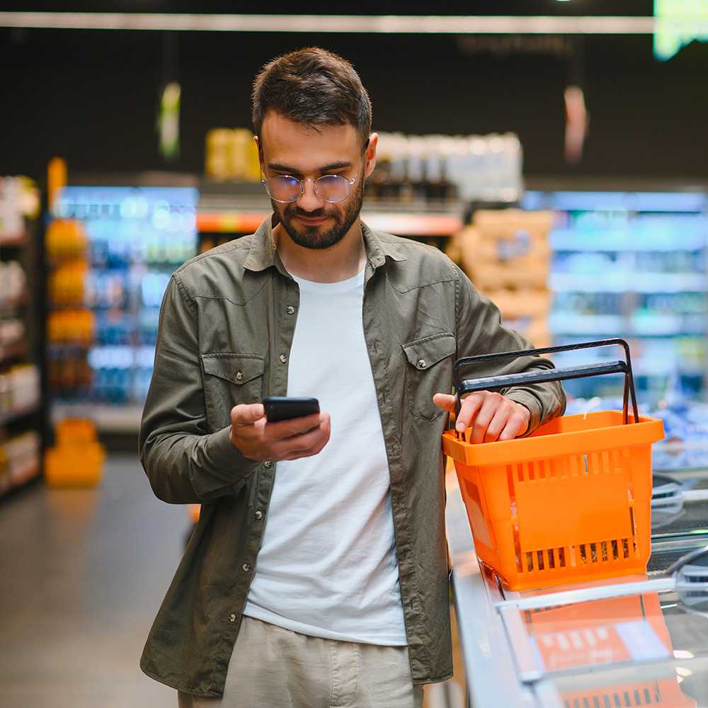 Man browsing on his phone in the vegetable section.
