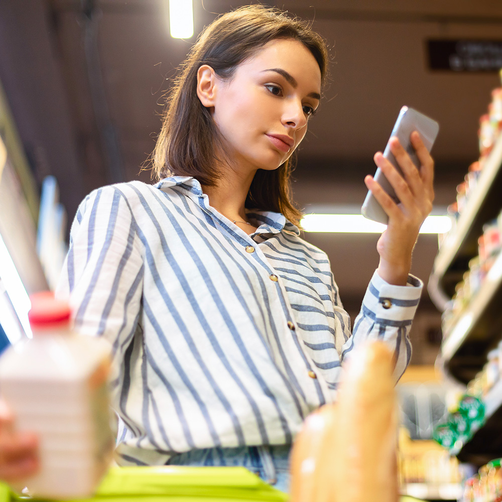 Fashionable woman checking her phone in a grocery store.